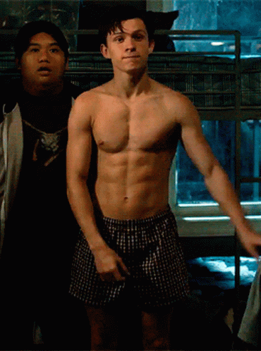 A Shirtless Man In Plaid Boxers Stands Next To Another Shirtless Man GIF