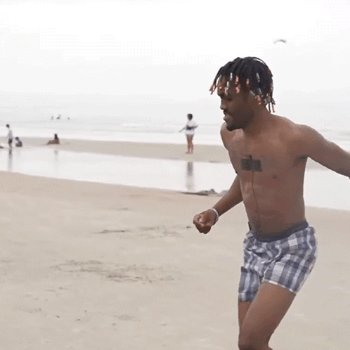 A Shirtless Man In Plaid Shorts Has A Tattoo On His Chest GIF