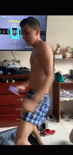A Shirtless Man In Plaid Shorts Is Dancing In Front Of A Television With The Number 11 On It GIF