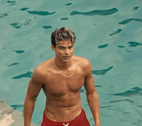 A Shirtless Man In Red Shorts Is Standing In A Pool GIF