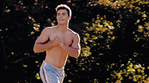 a shirtless man in shorts is running in a park