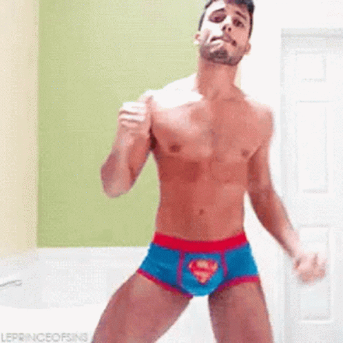 A Shirtless Man In Superman Underwear Is Dancing In A Room . GIF