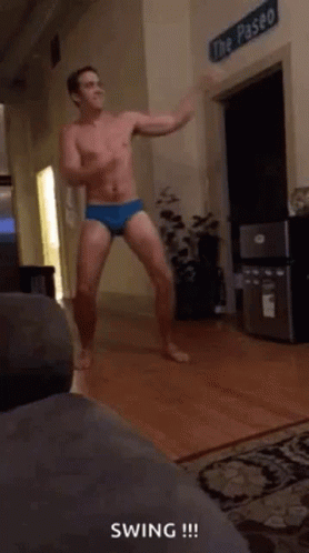 A Shirtless Man In Underwear Is Dancing In A Living Room GIF