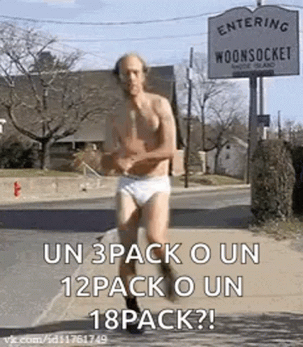 A Shirtless Man In Underwear Is Running Down A Street In Front Of A Sign That Says Entering Woonsocket . GIF