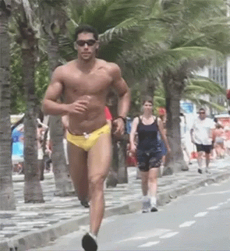 A Shirtless Man In Yellow Swim Trunks Is Running Down A Sidewalk GIF