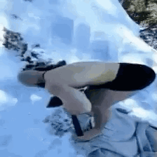 A Shirtless Man Is Bending Over In The Snow While Holding A Shovel . GIF