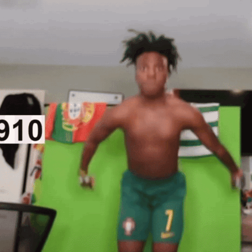 A Shirtless Man Is Dancing In Front Of A Green Screen With The Number 910 On It GIF