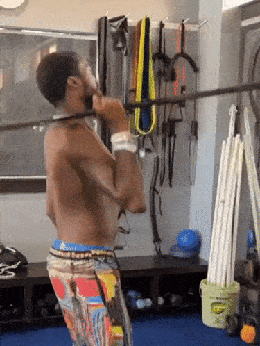 A Shirtless Man Is Doing A Pull Up In A Gym GIF
