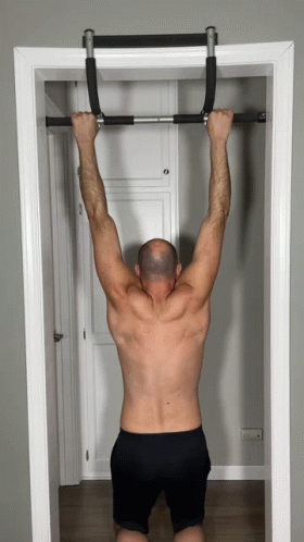 A Shirtless Man Is Doing Pull Ups On A Bar In A Doorway GIF