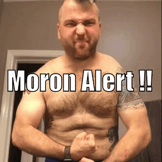 A Shirtless Man Is Flexing His Muscles With The Words Moron Alert Written On His Chest . GIF