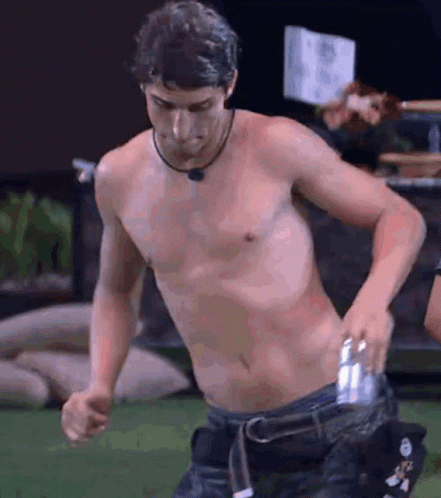 a shirtless man is holding a can in his pocket .