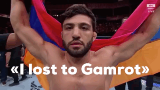 A Shirtless Man Is Holding A Colorful Flag And The Words Lost To Gamrot Are Above Him GIF
