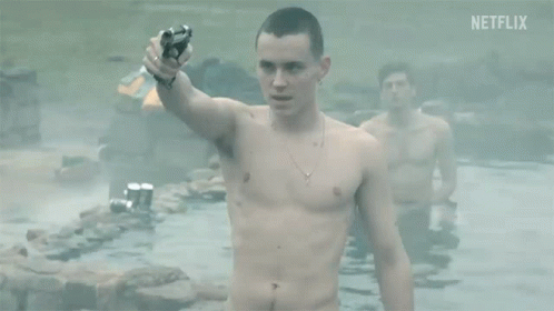 A Shirtless Man Is Holding A Gun While Standing In A Pool Of Water . GIF