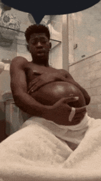 A Shirtless Man Is Holding His Pregnant Belly GIF