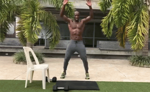 A Shirtless Man Is Jumping In The Air In Front Of A White Chair GIF