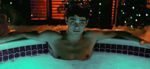 A Shirtless Man Is Laying In A Hot Tub Filled With Foam . GIF