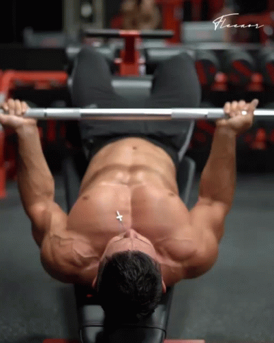 A Shirtless Man Is Lifting A Barbell In A Gym With The Word Fitness Written On The Bottom GIF