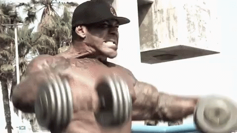A Shirtless Man Is Lifting A Pair Of Dumbbells In Front Of A Palm Tree GIF