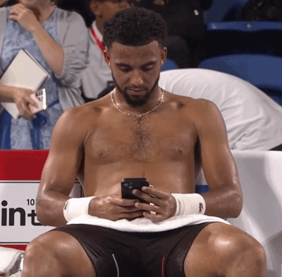 a shirtless man is looking at his cell phone in front of a sign that says 10