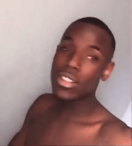 A Shirtless Man Is Making A Funny Face While Taking A Selfie . GIF
