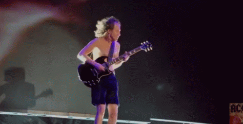 A Shirtless Man Is Playing A Guitar On Stage In Front Of A Sign That Says Ac GIF