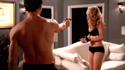 A Shirtless Man Is Pointing A Gun At A Woman In Black Underwear GIF