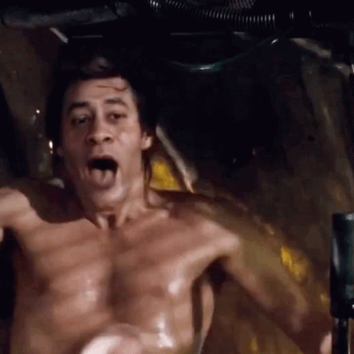A Shirtless Man Is Sitting In A Bathtub With His Mouth Open And His Tongue Out . GIF