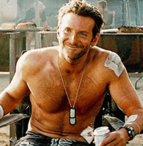 A Shirtless Man Is Sitting In A Chair Holding A Can Of Beer GIF