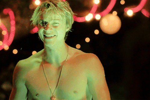 A Shirtless Man Is Smiling In Front Of A Neon Sign That Says ' I Love You ' GIF
