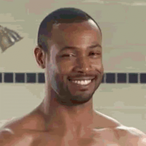 A Shirtless Man Is Smiling While Taking A Shower . GIF