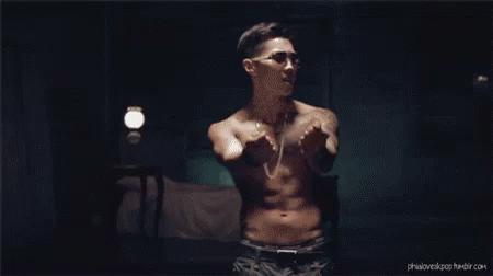 a shirtless man is standing in a dark room with his arms outstretched .
