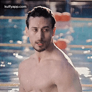 A Shirtless Man Is Standing In A Pool . GIF