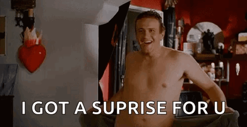 A Shirtless Man Is Standing In A Room With A Heart On The Wall . GIF