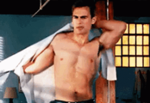 A Shirtless Man Is Standing In A Room With His Shirt Off . GIF