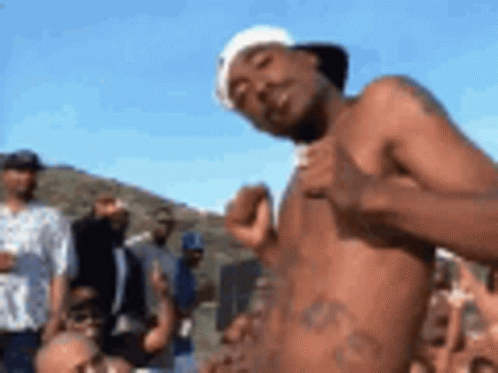A Shirtless Man Is Standing In Front Of A Group Of People . GIF