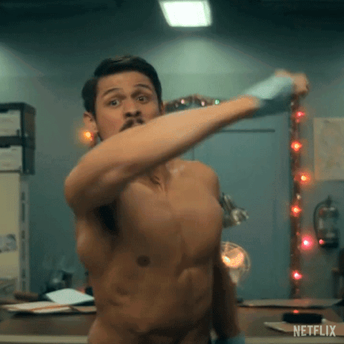 a shirtless man is standing in front of a mirror and holding a hammer .