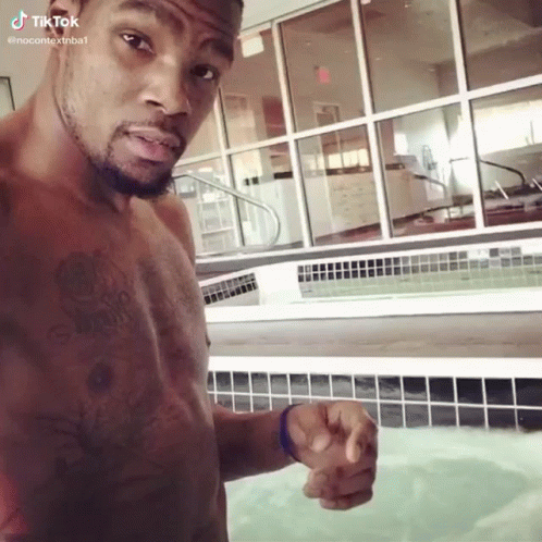 A Shirtless Man Is Standing In Front Of A Pool And Pointing GIF