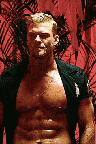 A Shirtless Man Is Standing In Front Of A Red Wall With A Palm Tree In The Background GIF