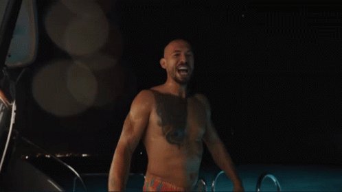 A Shirtless Man Is Standing In Front Of A Sign That Says Edom GIF