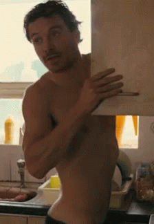 A Shirtless Man Is Standing In Front Of A Sink Holding A Piece Of Paper GIF