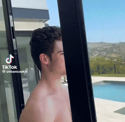 a shirtless man is standing in front of a sliding glass door with tiktok written on the bottom right corner