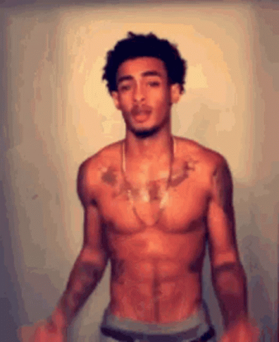 A Shirtless Man Is Standing In Front Of A Wall . GIF