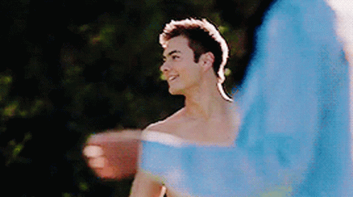 a shirtless man is standing next to another shirtless man in a blue jacket