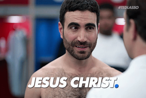A Shirtless Man Is Talking To Another Shirtless Man With The Words Jesus Christ Written On His Chest GIF
