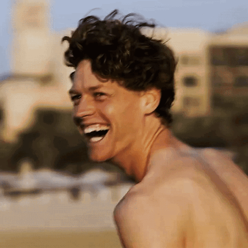 A Shirtless Man Laughs With His Mouth Open GIF