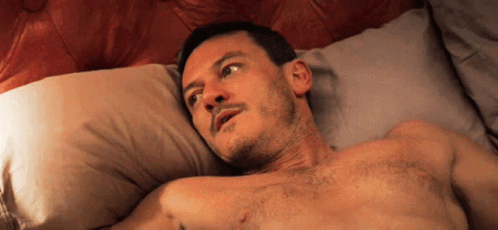 A Shirtless Man Laying On A Bed Looking Up GIF