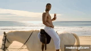 A Shirtless Man Riding A White Horse On A Beach GIF