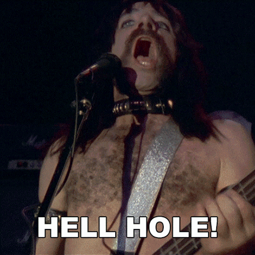 A Shirtless Man Singing Into A Microphone And Playing A Guitar With The Words Hell Hole Below Him GIF