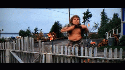 A Shirtless Man Standing In Front Of A Wooden Fence GIF