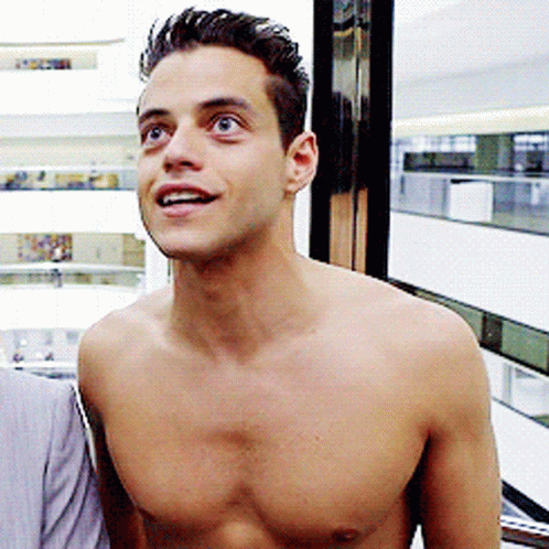 A Shirtless Man Stands In Front Of A Window And Smiles GIF